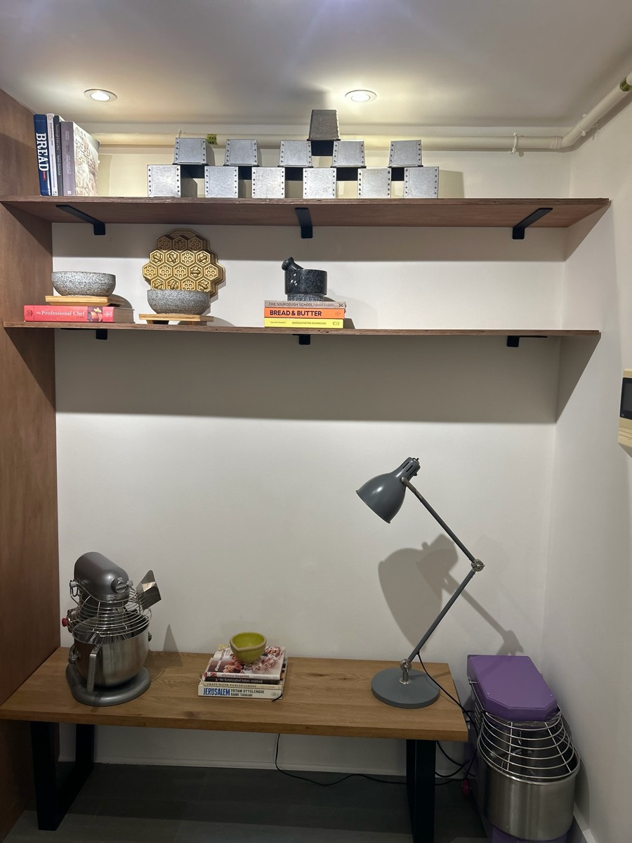 Open shelving holding the client's baking tins, cookbooks and stand mixer on a dedicated worktop