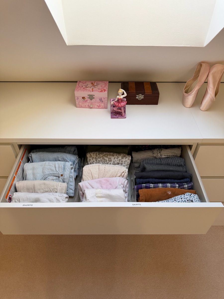 Drawer organised by Studio 14 with shorts and skirts in labelled dividers, ballet shoes displayed on the wardrobe shelf above