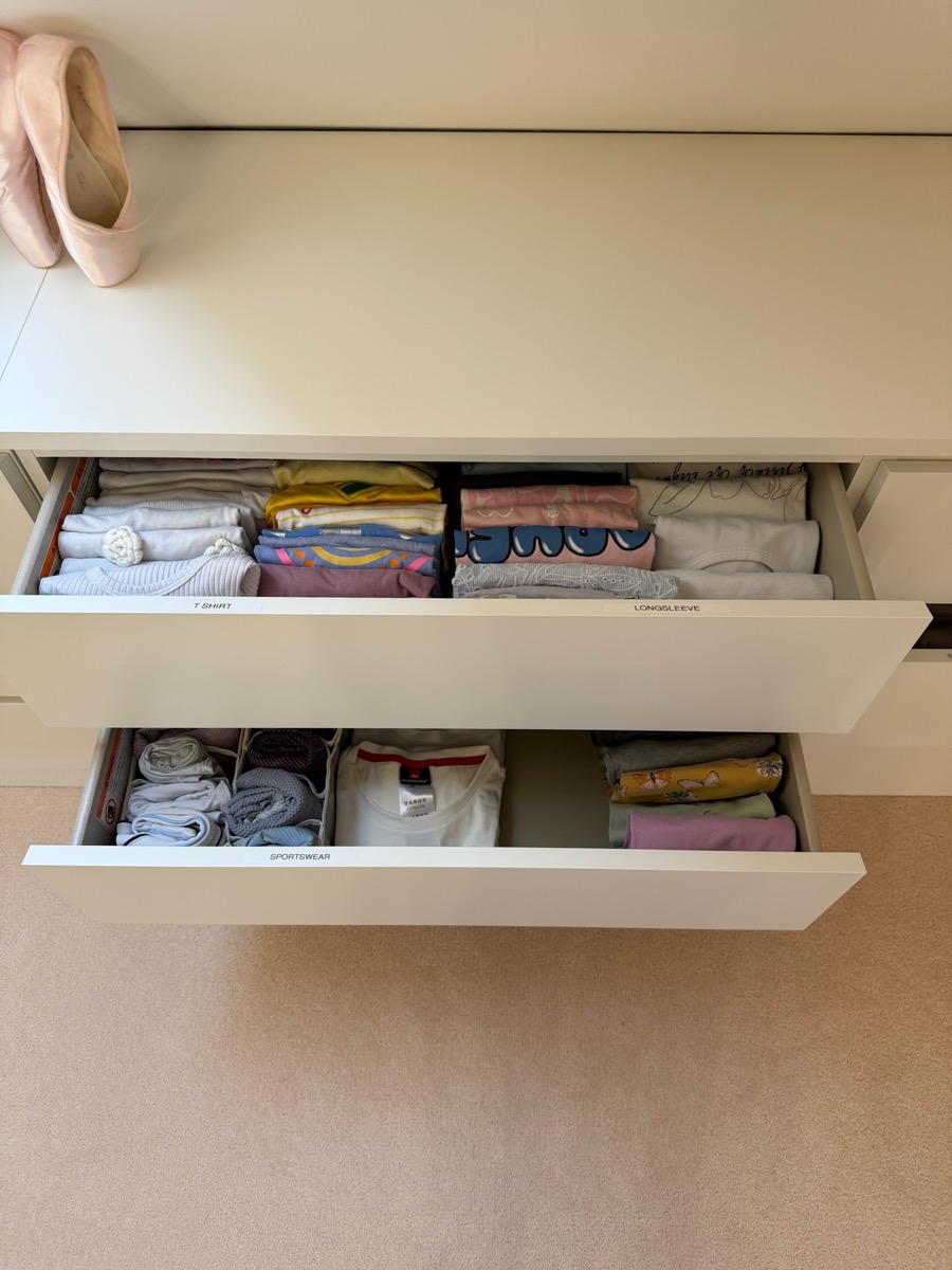 Wardrobe drawers organised by Studio 14, labelled T-shirt, longsleeve and sportswear, with clothes folded upright