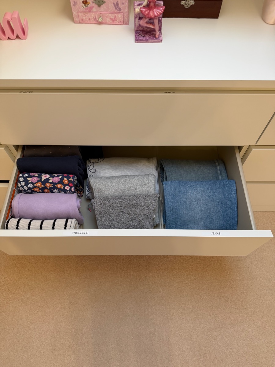 Wardrobe drawer organised by Studio 14 with trousers and jeans folded upright in labelled sections