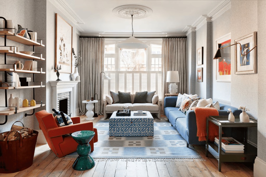 Open-plan living space styled by Studio 14 with open shelving, a blue sofa and a terracotta armchair